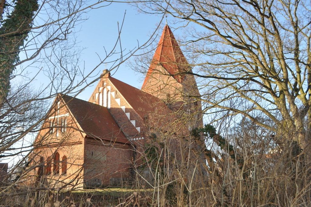 En kirke med et markant tårn og en mindre bygning med saddeltag.