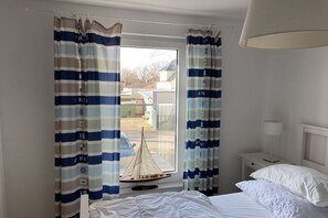 A hotel room with a bed, a nightstand, a lamp, and curtains. - Baltic Sea Oasis Rerik (Ostseebad Rerik)