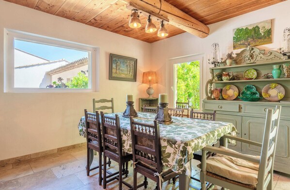 A dining area with a table set for four, wooden chairs, a chandelier, and a view of the outside. - Aesthetic Villa in Paradou, Alpilles (Paradou)
