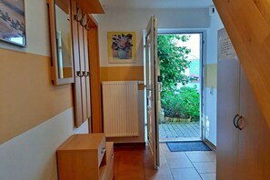 A narrow hallway with a radiator, a wooden cabinet, and a door leading to a garden. - Reiche family holiday apartments (Ahlbeck (Seebad))