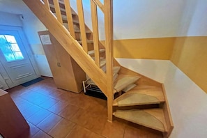 A wooden staircase with a landing area, a white door with a window, and a tiled floor. - Reiche family holiday apartments (Ahlbeck (Seebad))