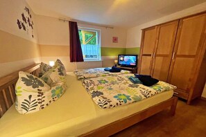 Een slaapkamer met een bed, een televisie en een kledingkast.