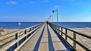 Une promenade en bois menant à la plage, avec un ciel dégagé.