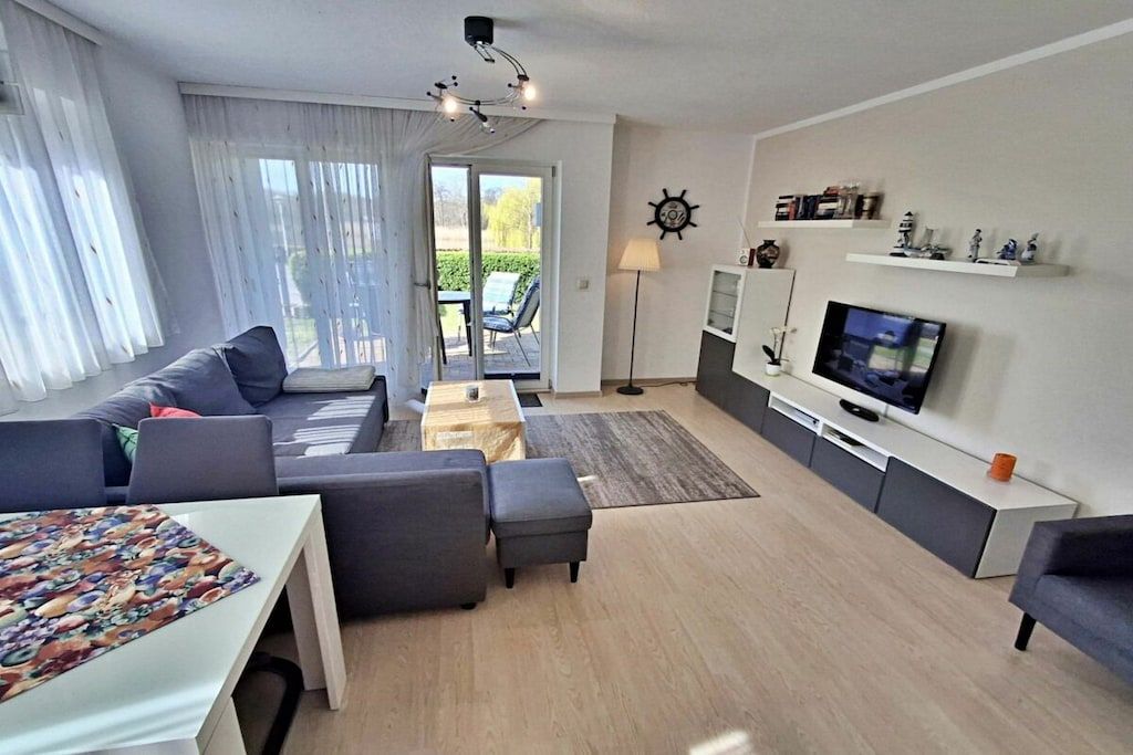 Een moderne woonkamer met een bank, een salontafel, een televisie en een eethoek.