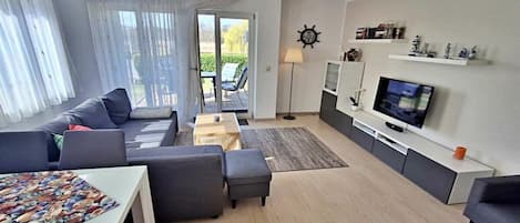 Een moderne woonkamer met een bank, een salontafel, een televisie en een eethoek.