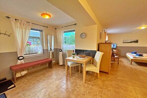 Ein gemütliches Zimmer mit Esstisch, Bank und Fernseher.
