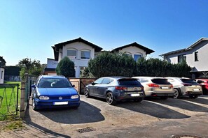 Ein Parkplatz mit mehreren Autos, ein Gebäude mit einem geneigten Dach und einem wolkenlosen Himmel.