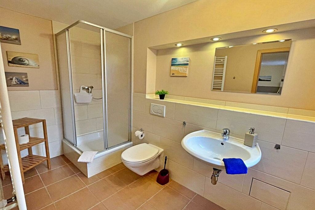 Ein Badezimmer mit Duschkabine, Toilette, Waschbecken und Spiegel.