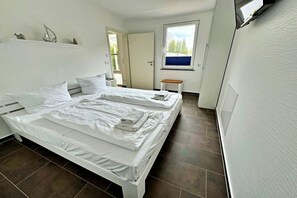 A hotel room with two beds, a small table, and a window with a view of trees. - Holiday apartment Altenberg 02 (Ahlbeck (Seebad))