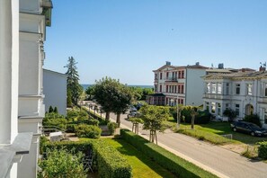 Eine Wohnstraße mit einer Reihe von Häusern, einem klaren Himmel und einem entfernten Blick auf das Meer.