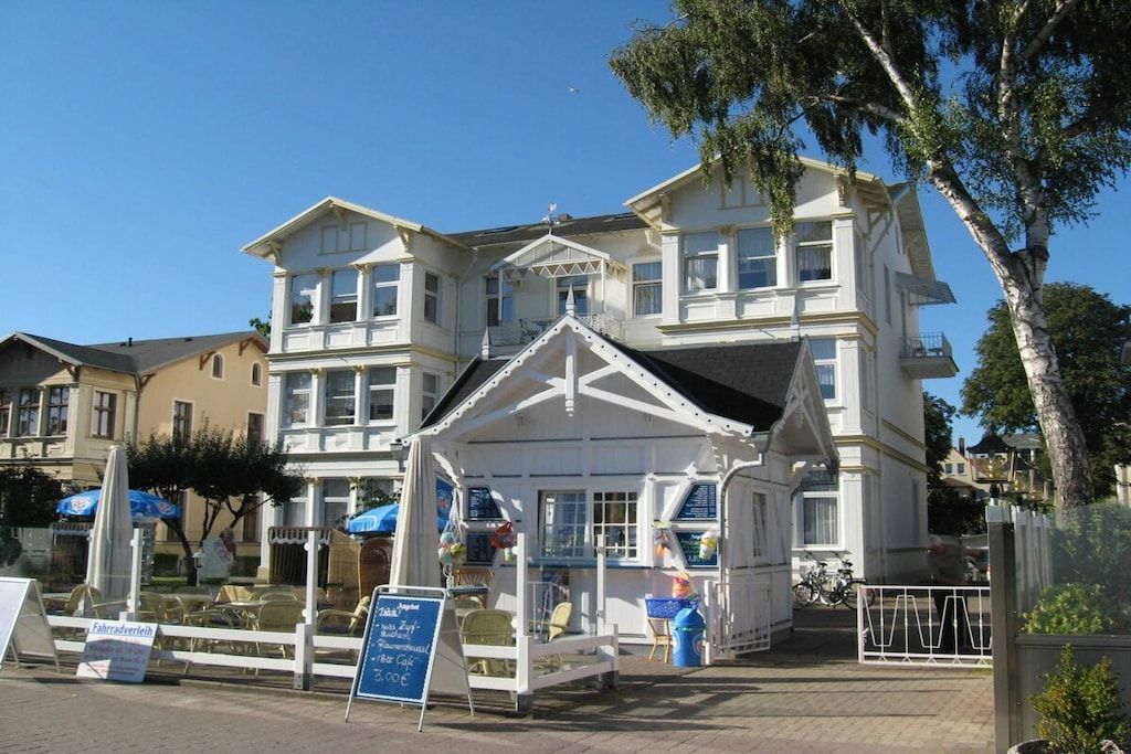 A two-story building with a balcony and a small attached structure with a roof.