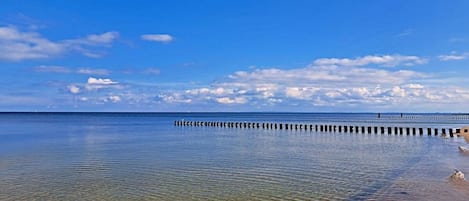 On peut admirer une mer calme et dégagée, avec une jetée en bois qui s’avance dans l’eau.