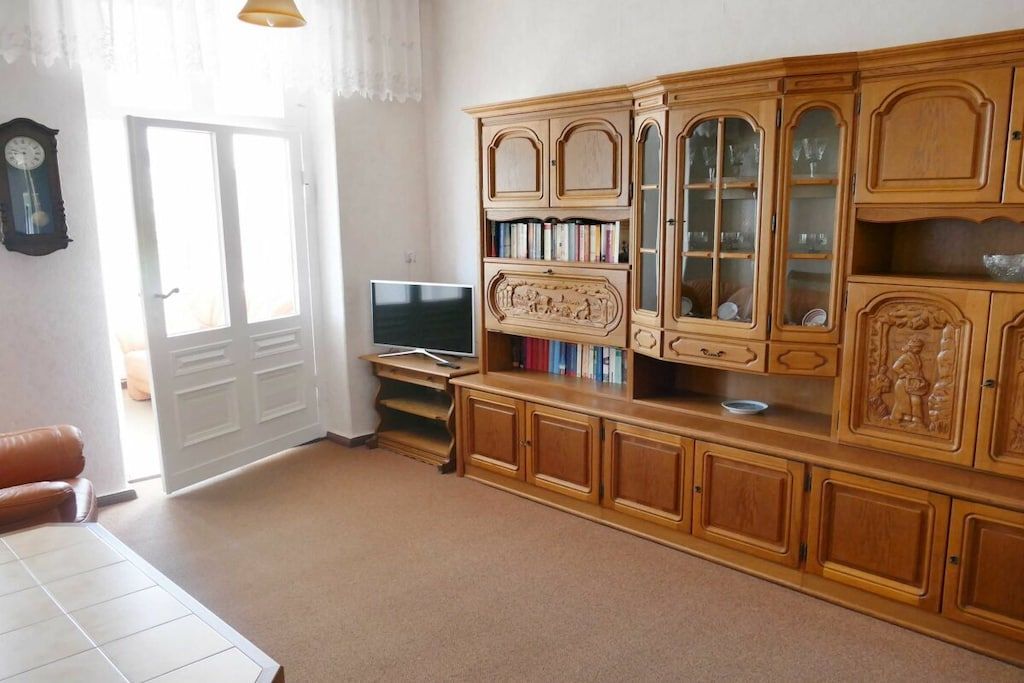 A living room with a wooden cabinet, a television, and a door.