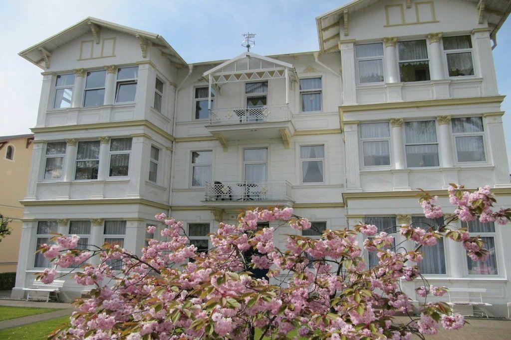 A multi-story building with a symmetrical facade, large windows, and a central balcony.