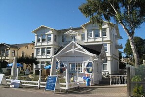 A two-story building with a balcony and a small attached structure with a roof. - Holiday apartment with 1 bedroom (Ahlbeck (Seebad))