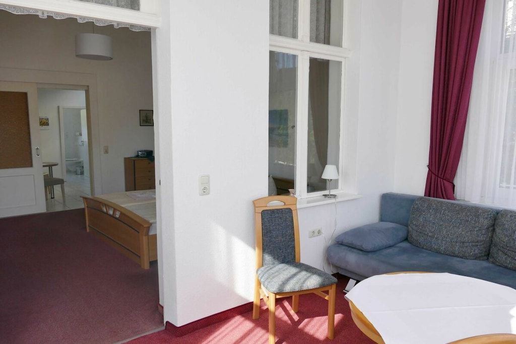 Ein Zimmer mit einem Bett, einem Sessel, einer Couch und einem Fenster.