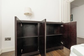 Une pièce avec un meuble en bois foncé doté de plusieurs étagères, un mur blanc et une lampe.