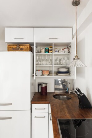 A modern kitchen with white cabinetry, a wooden countertop, a built-in stove, and a hanging pendant light. - New! Spacious 1BR Flat | Marble Arch | Hyde Park (Greater London)