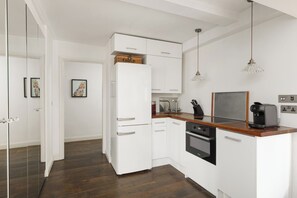 Une cuisine moderne avec des meubles blancs, un plan de travail en bois et un four encastré.