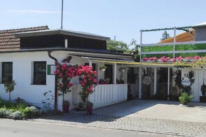Ein Gebäude mit weißer Fassade, einem überdachten Eingang und der Zahl 13 auf der rechten Seite.