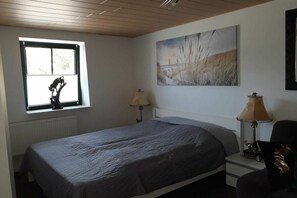 Ein Schlafzimmer mit einem Einzelbett, zwei Nachttischlampen, einem Fenster mit Blick und einem Bild an der Wand.