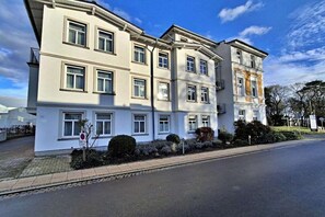 A multi-story building with a flat facade, large windows, and a gated entrance. - House by the spa park (Ahlbeck (Seebad))
