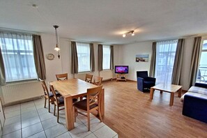A modern living room with a wooden dining table, chairs, a television, and a sofa. - House by the spa park (Ahlbeck (Seebad))