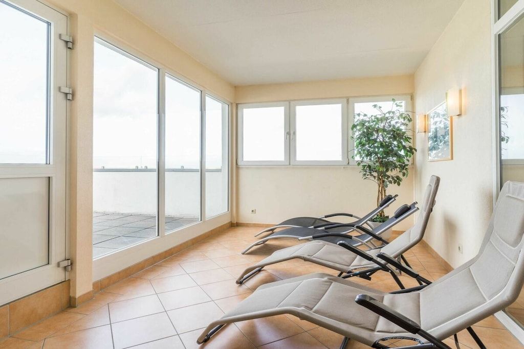 A waiting area with chairs, large windows, and a potted plant.