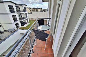 A balcony with a table and chairs, a view of neighboring buildings, and a clear sky. - House by the spa park (Ahlbeck (Seebad))