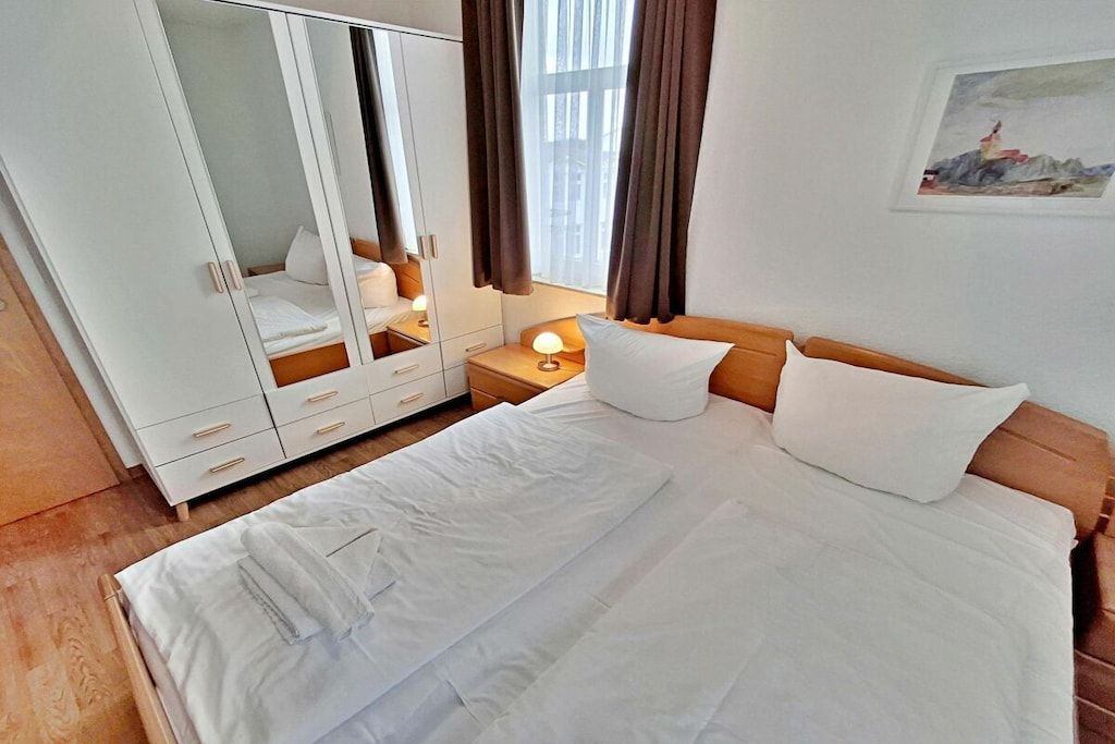 Una camera da letto con un letto, un armadio, un comodino e un quadro appeso al muro.