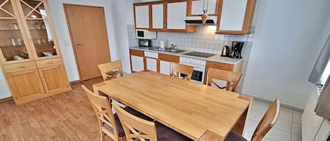 A compact kitchen with wooden cabinets, a dining table with chairs, and a built-in oven.