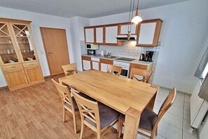 Eine kompakte Küche mit Holzausstattung, einem Esstisch mit Stühlen und einem eingebauten Backofen.