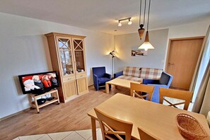 Un espacio habitable compacto con una televisión, un sofá, una mesa de comedor y un armario.