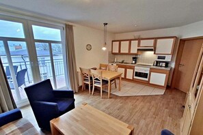 A compact living space with a dining area, kitchen, and a balcony with a view. - House by the spa park (Ahlbeck (Seebad))