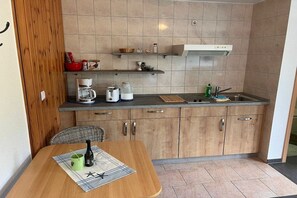 Eine kleine Küche mit Essbereich, ausgestattet mit einer Kaffeemaschine, einem Wasserkocher und einem Spülbecken.