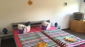 Una camera d'albergo con due letti, una televisione e un piccolo mobiletto.
