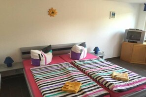 Quarto de hotel com duas camas, televisão e um pequeno armário.