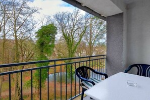 A balcony with a table and chairs, overlooking a wooded area. - Residenz am Buchenpark App. 14 (Heringsdorf (Seebad))