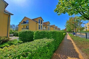 A residential street with yellow houses, a paved walkway, and green hedges. - Schloonseevillen Bansin Apartment 15 (Bansin (Seebad))