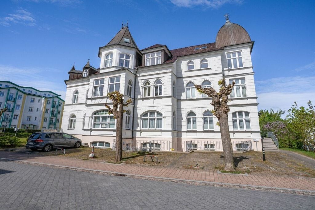 A large, multi-story building with a classic architectural style, featuring arched windows and a prominent dome on the top right.