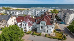 Ett bostadsområde vid kusten med flerfamiljshus, en strand i bakgrunden och en klar himmel.