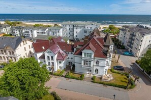 Ein Küstenwohngebiet mit mehrstöckigen Gebäuden, einem Strand im Hintergrund und einem klaren Himmel.