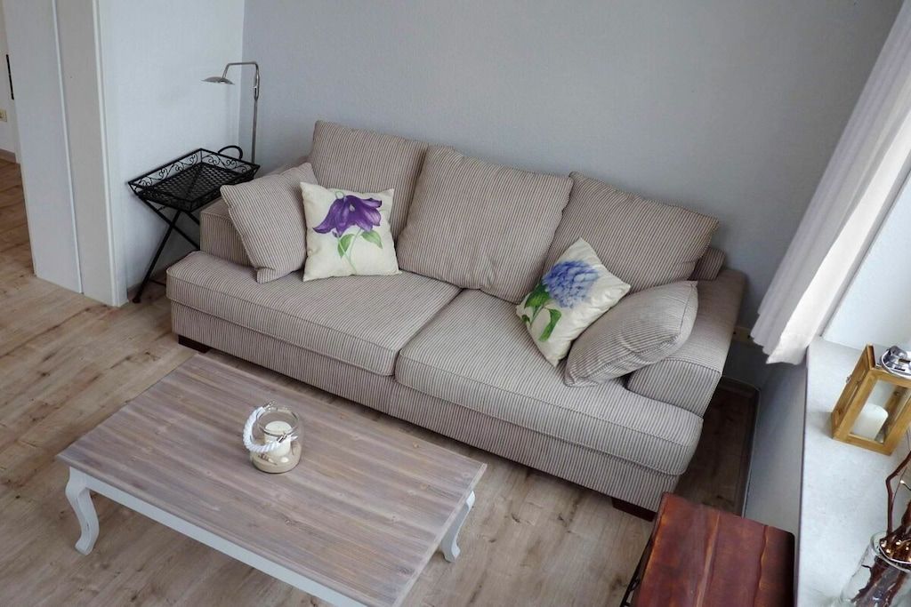 Een woonkamer met een gestreept bankje, een bijzettafeltje en een vloerlamp.