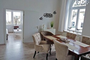 Un coin repas comprenant une table en bois et quatre chaises, un meuble blanc et une décoration murale représentant des poissons.