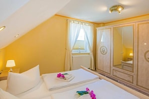 Een hotelkamer met een bed, nachtkastje, spiegel en kledingkast.
