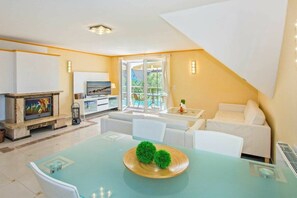 A modern living room with a dining table, sofa, and a fireplace. - Holiday apartment with 1 bedroom (Heringsdorf (Seebad))