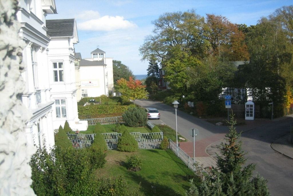 Eine Wohnstraße mit einem weißen Gebäude, einem geparkten Auto und einem Briefkasten.