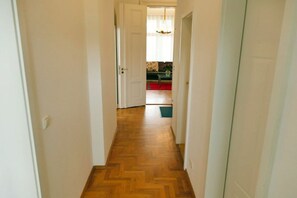 A hallway with wooden flooring leading to a room with a red carpet and a green rug. - Villa Franz Josef 04 (Heringsdorf (Seebad))