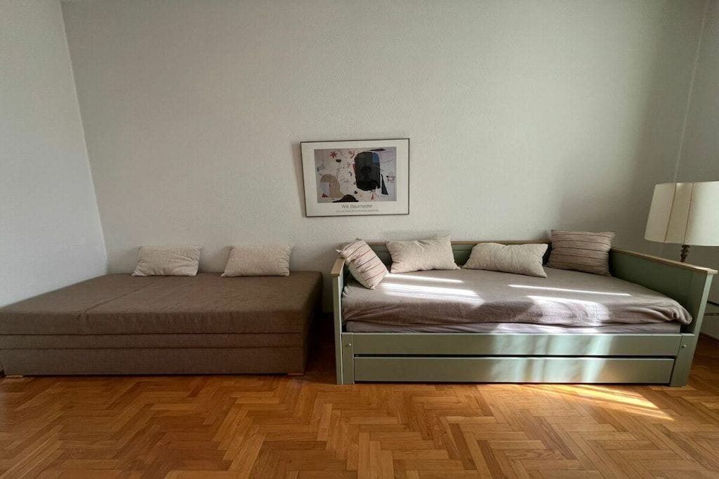 Ein Zimmer mit einem Bett, einem Schlafsofa und einem gerahmten Bild an der Wand.