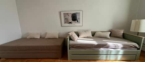 Ein Zimmer mit einem Bett, einem Schlafsofa und einem gerahmten Bild an der Wand.